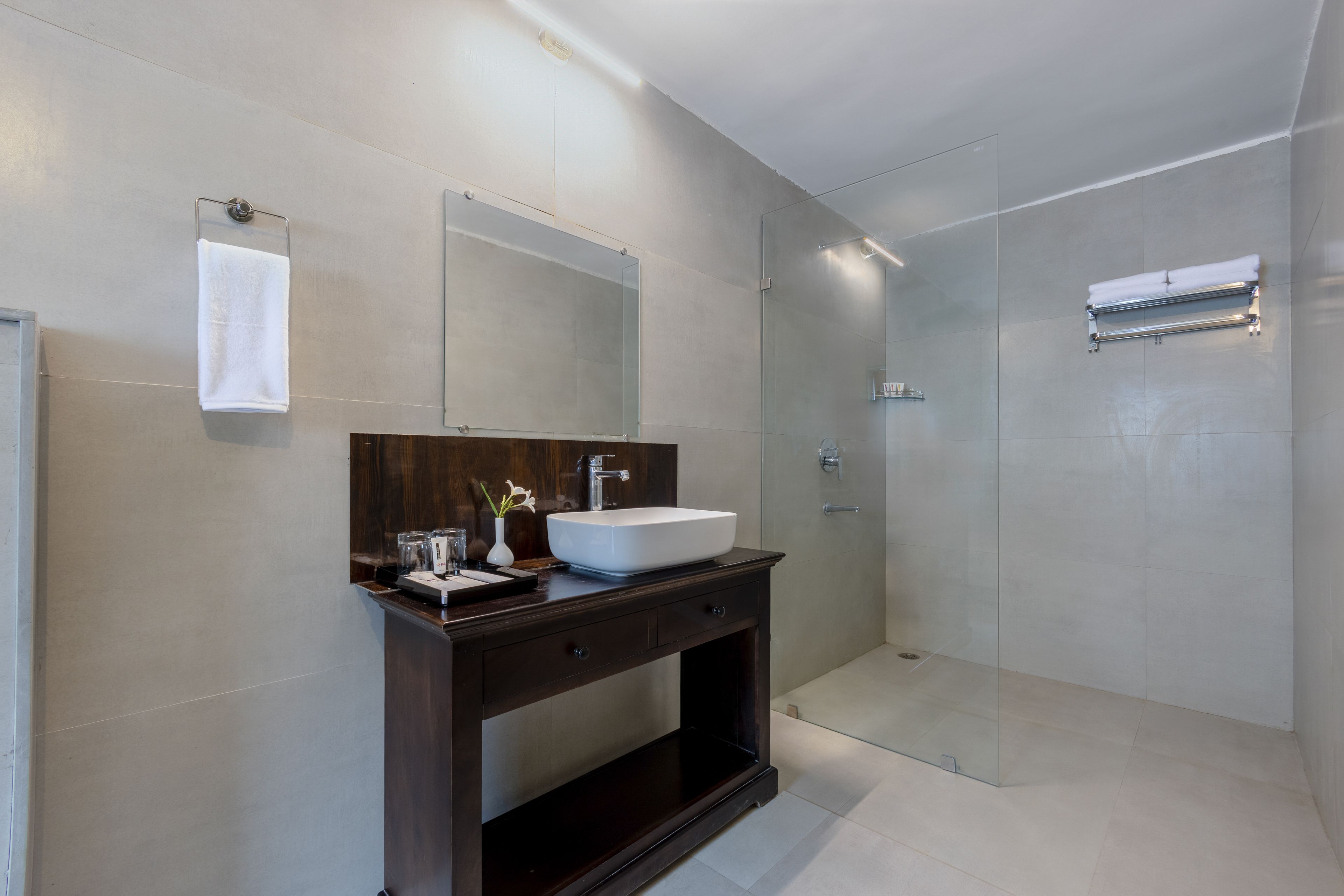 Een moderne badkamer met een grote spiegel, een witte wastafel en een douche met glazen wanden.