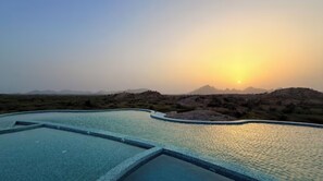 A swimming pool with a sunset in the background.