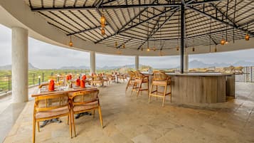 A spacious outdoor dining area with high ceilings and a view of the landscape.