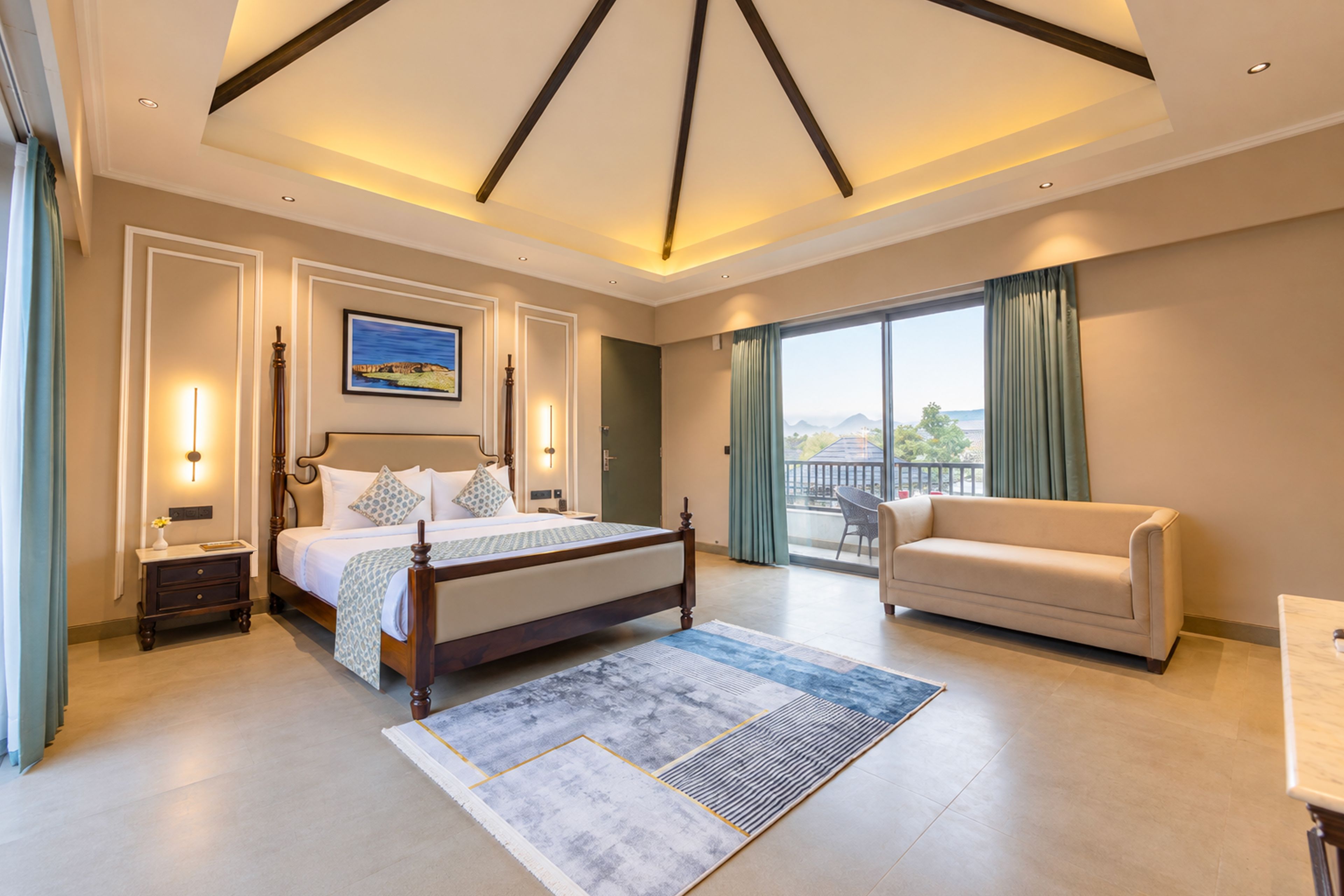 A hotel room with a large bed, a sofa, a balcony with a view, and a painting on the wall.