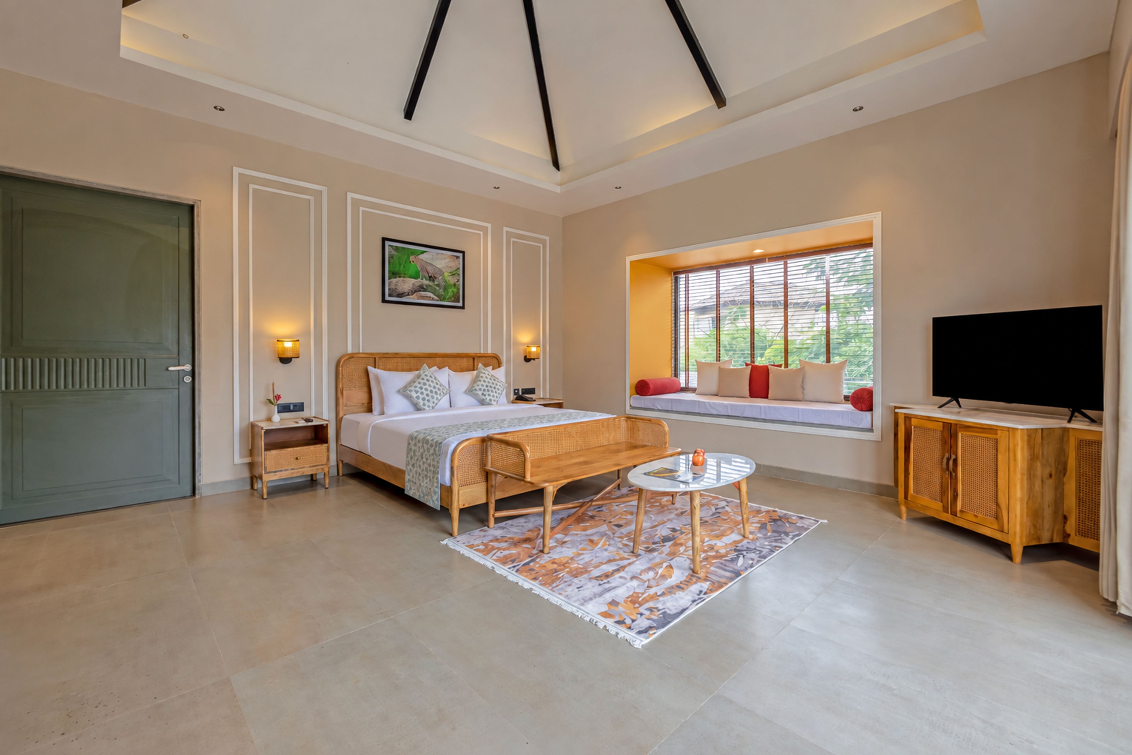 A modern bedroom with a large bed, bedside tables, a TV, and a window with blinds.