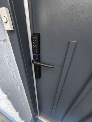 A door with a keypad lock and a handle. - 3 bed Modern Apartment near Glasgow city Centre,Glasgow airport and Loch Lomond (Clydebank)