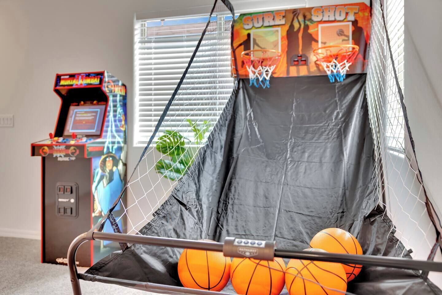 A basketball arcade game with a netted backboard and three basketballs.