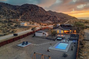 A residential property with a swimming pool, outdoor seating, and a view of a mountainous landscape.