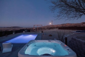 A hot tub and a rectangular pool in a backyard with a swing set and desert landscape in the background. - Pool, Hot Tub, Stars, Views, Yoga Pad, Bocce, BBQ (Joshua Tree)