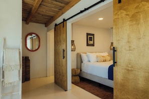 A bedroom with a bed, a wooden door, a mirror, and a framed picture on the wall. - Pool, Hot Tub, Stars, Views, Yoga Pad, Bocce, BBQ (Joshua Tree)
