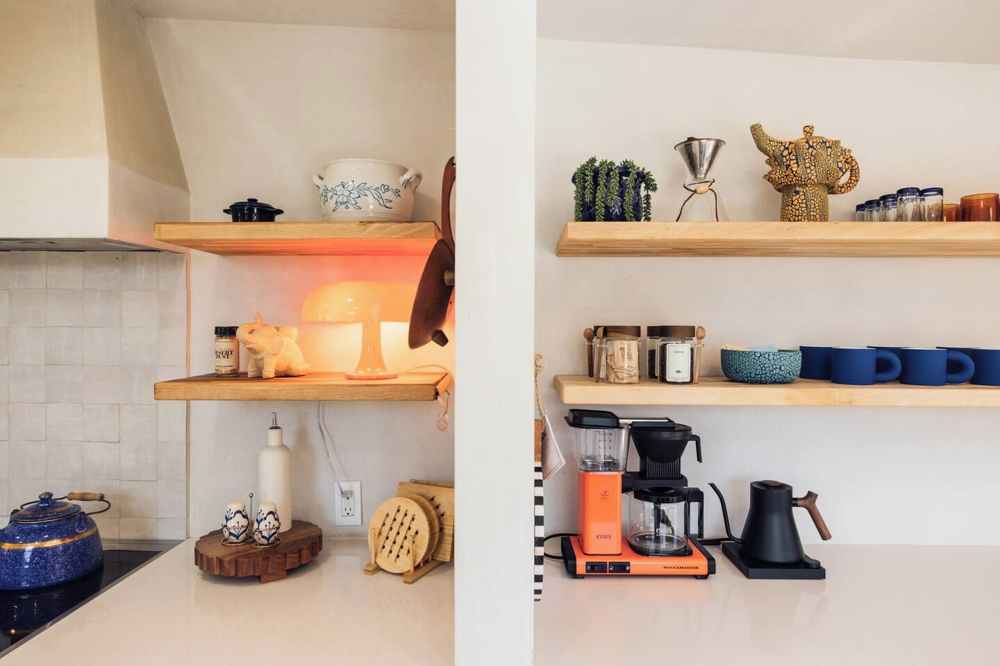 Una cocina con estantes de madera, una cafetera y un hervidor.
