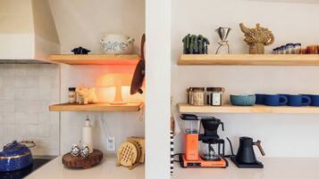 Una cocina con estantes de madera, una cafetera y un hervidor.