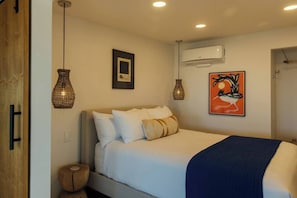 A bedroom with a bed, bedside lamps, an air conditioning unit, and a wall-mounted artwork. - Pool, Hot Tub, Stars, Views, Yoga Pad, Bocce, BBQ (Joshua Tree)