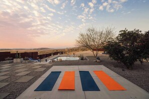 An outdoor patio with a pool, exercise mats, and a view of the desert landscape.