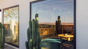 Un interior moderno con un gran ventanal, una planta de cactus, un sofá y una mesa.