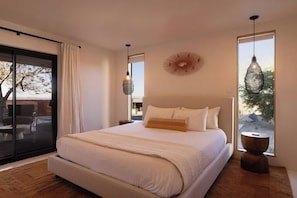 A modern bedroom with a large bed, a sliding glass door leading to an outdoor area, and a unique wall decoration. - Pool, Hot Tub, Stars, Views, Yoga Pad, Bocce, BBQ (Joshua Tree)