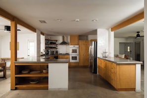 A modern kitchen with wooden cabinets, a central island, and built-in appliances.