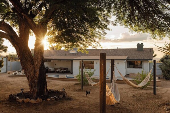 A house with a covered patio, a swimming pool, and a hammock.