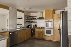 A modern kitchen with wooden cabinets, stainless steel appliances, and a brick backsplash. - Black Rock Retreat - Desert Escape with Pool, Spa & Hammocks (Yucca Valley)
