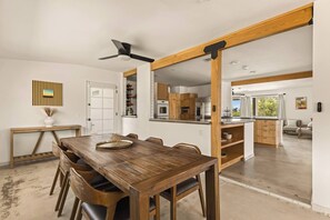 A modern kitchen with wooden cabinets, a dining area with a large table and chairs, and a ceiling fan. - Black Rock Retreat - Desert Escape with Pool, Spa & Hammocks (Yucca Valley)