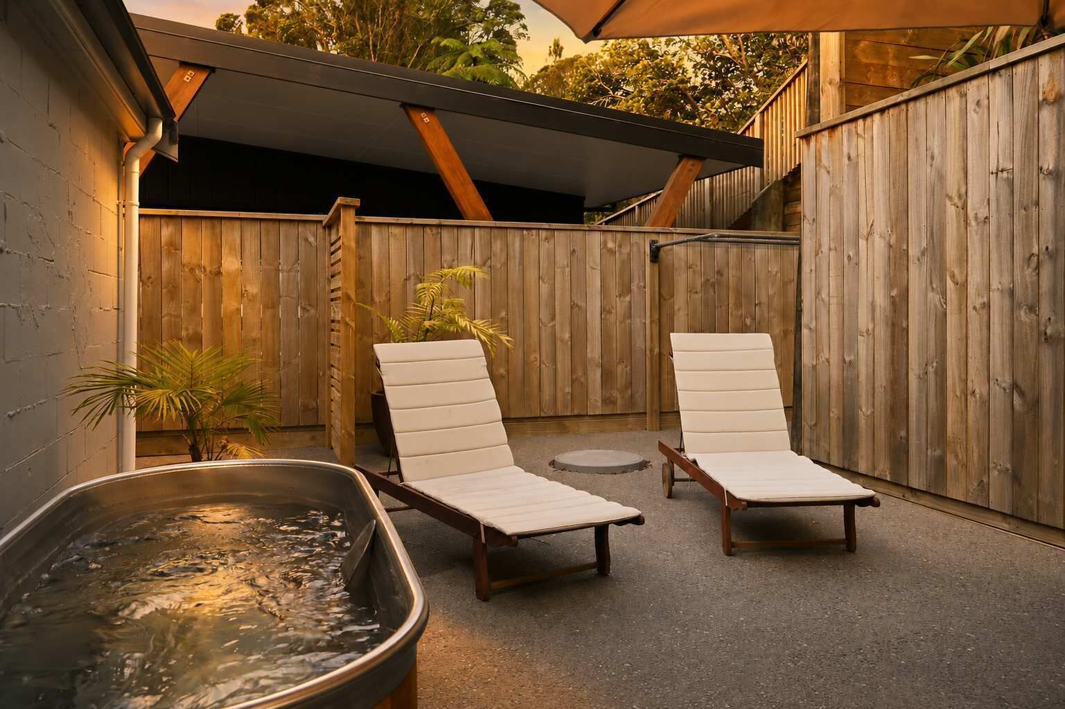 Un patio trasero con dos sillones, un jacuzzi y un cerco de madera.