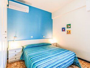 Et soveværelse med seng, sengeborde, en aircondition og billedkunst på væggen.
