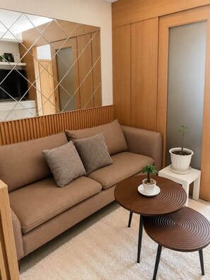 Ein modernes Wohnzimmer mit einer Couch, zwei Kissen, einem Couchtisch mit einer Pflanze und einem kleinen Beistelltisch.