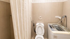 Et badeværelse med bruser, toilet og vaskemaskine.