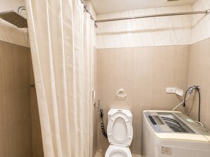 Ein Badezimmer mit Dusche, Toilette und Waschmaschine.