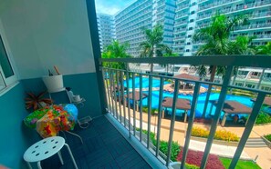 Ein Balkon mit Blick auf einen Pool und hohe Gebäude.