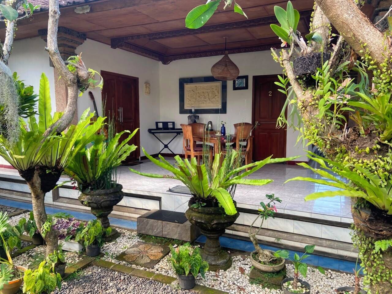 A tropical garden with potted plants and a traditional wooden structure.