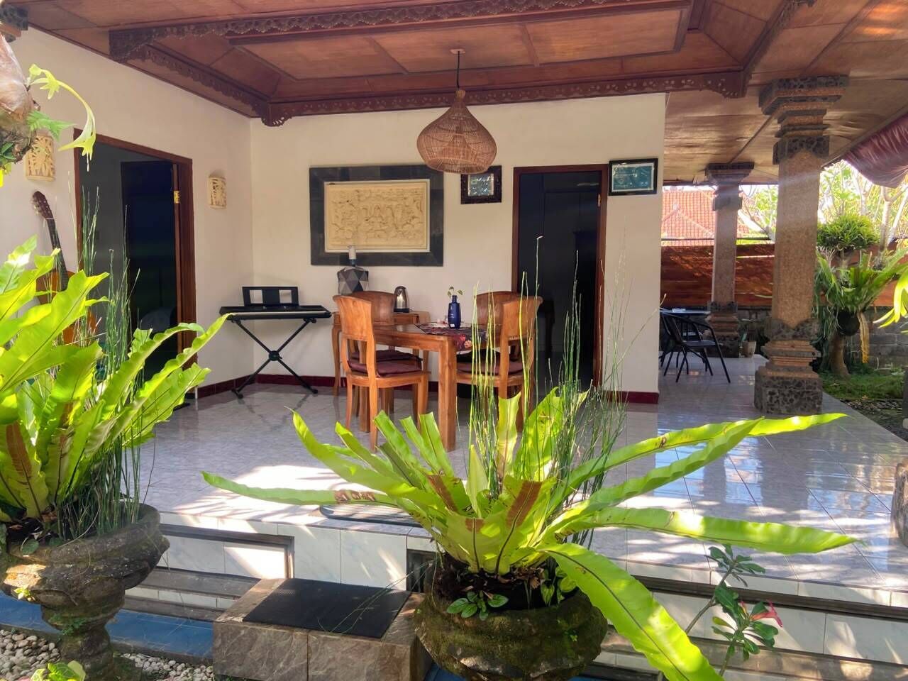 An outdoor patio with a dining table and chairs, surrounded by potted plants.