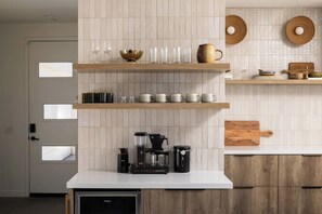 Une cuisine avec des étagères en bois, une machine à café et une planche à découper en bois.