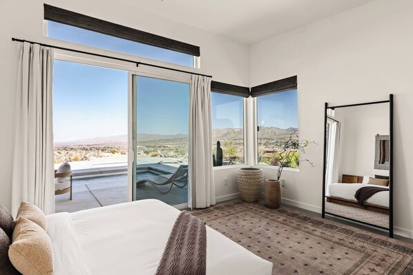 Une chambre d’hôtel avec un grand lit, un coin salon avec vue et un balcon donnant sur la piscine.