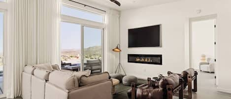 Una sala de estar moderna con sofá, una mesa de centro, chimenea y televisión montada en la pared.