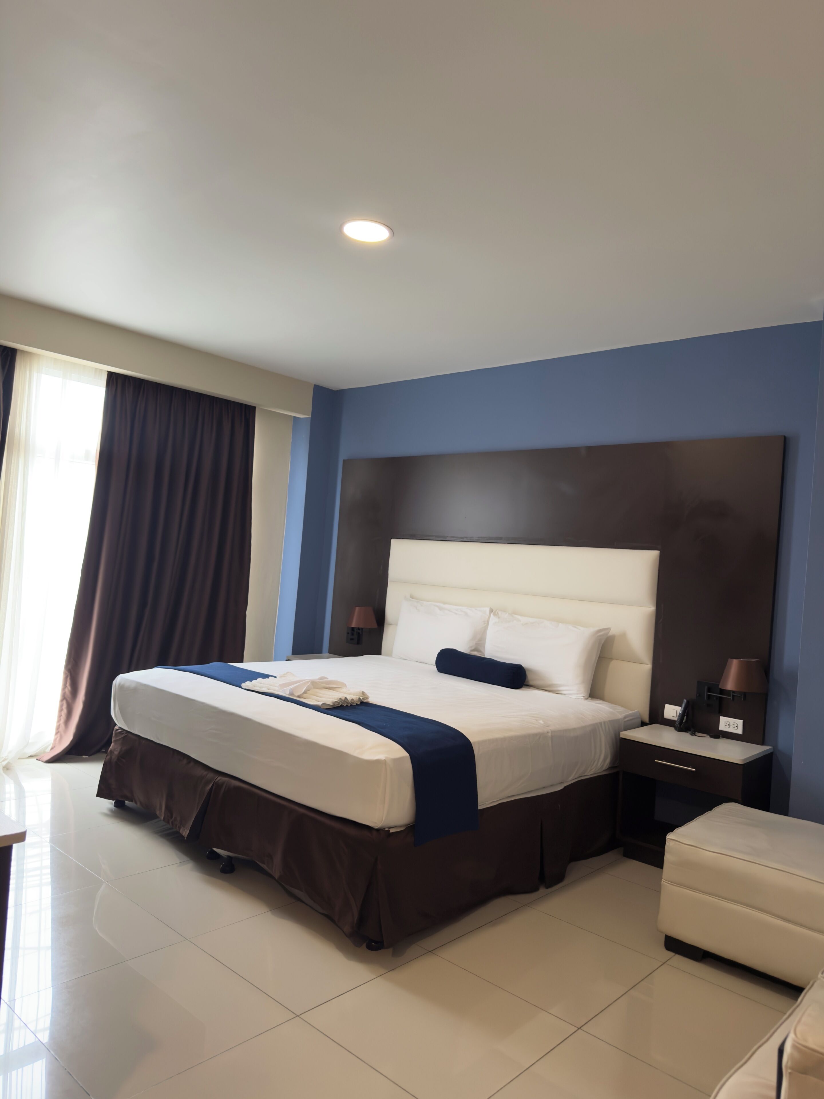 A hotel room with a large bed, bedside tables, a desk, and a chair.