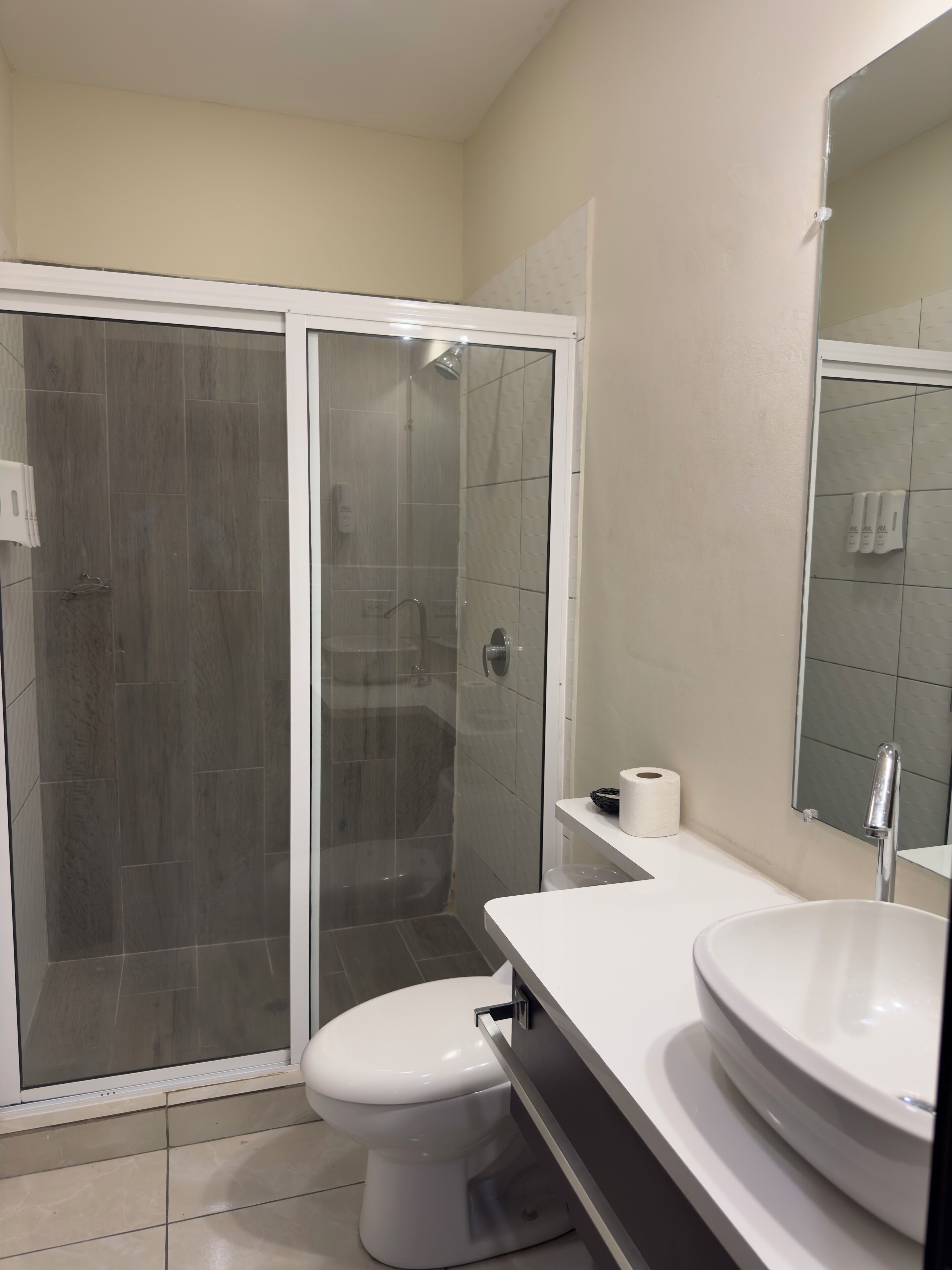 Un baño con cabina de ducha, inodoro y lavabo con espejo.
