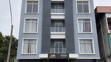 A multi-story hotel with a modern facade, a black garage door, and a white car parked in front.