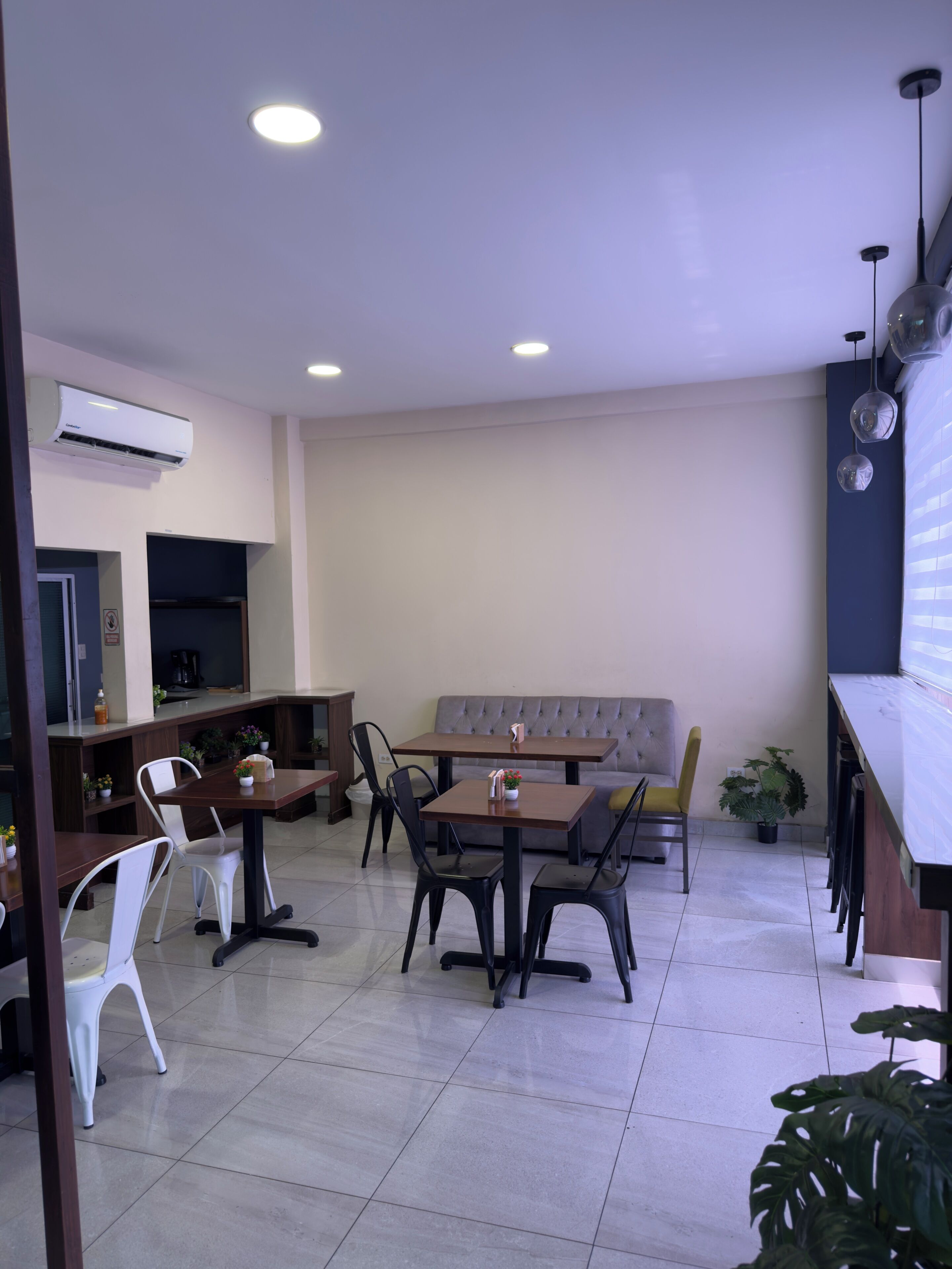 A modern dining area with a sofa, tables, chairs, and a coffee machine.