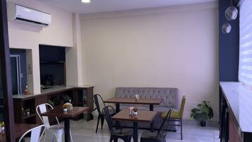 A modern dining area with a sofa, tables, chairs, and a coffee machine.