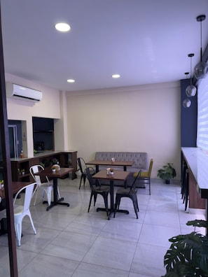 A modern dining area with a sofa, tables, chairs, and a coffee machine. - Merendón Suites (San Pedro Sula)