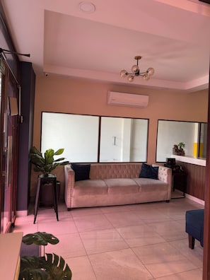 A living room with a sofa, a potted plant, a small table, and a ceiling fan. - Merendón Suites (San Pedro Sula)