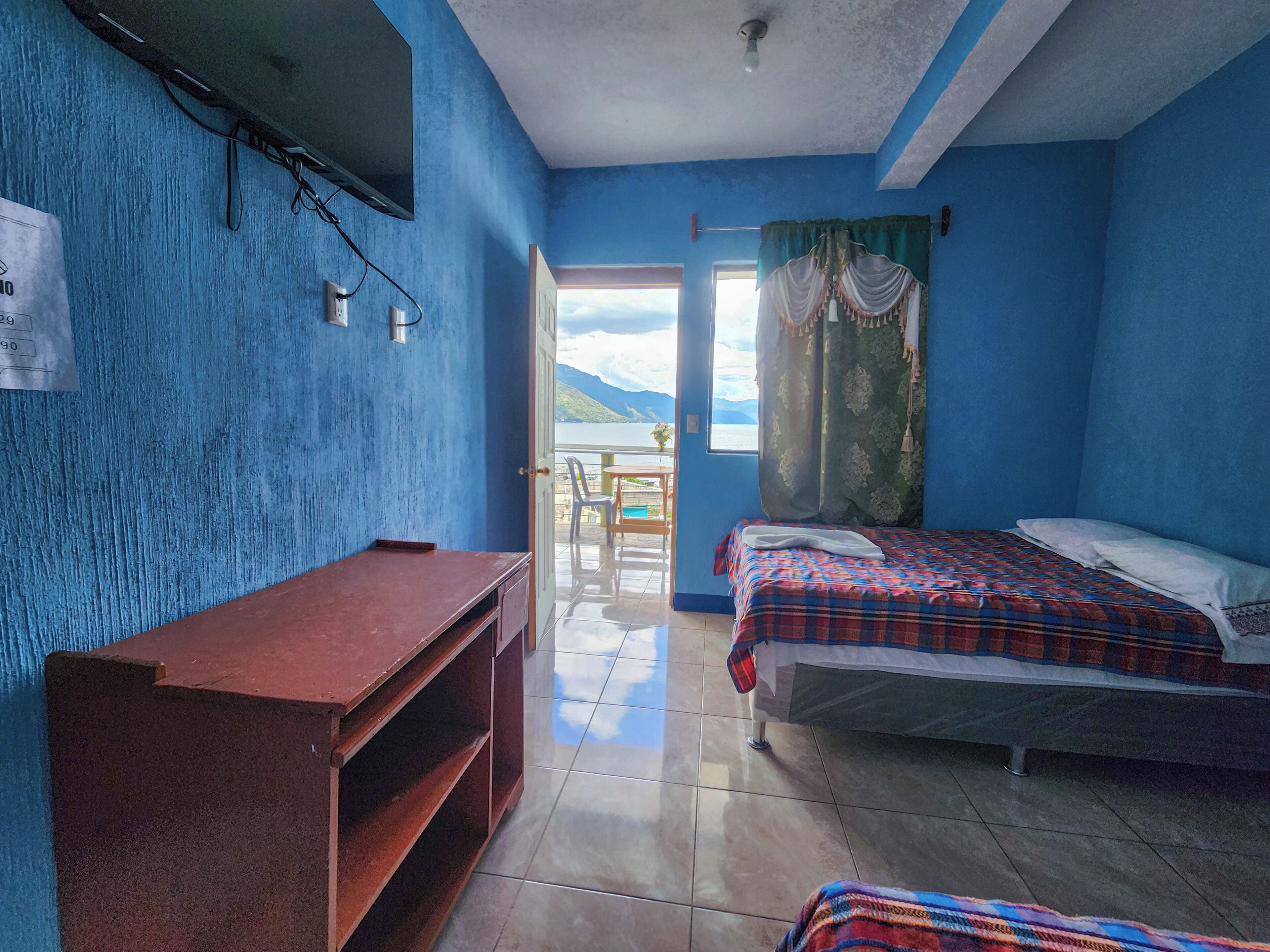 Una habitación con cama, escritorio y vista al exterior.