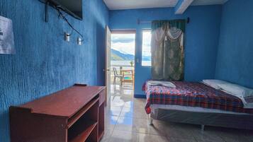 Una habitación con cama, escritorio y vista al exterior.