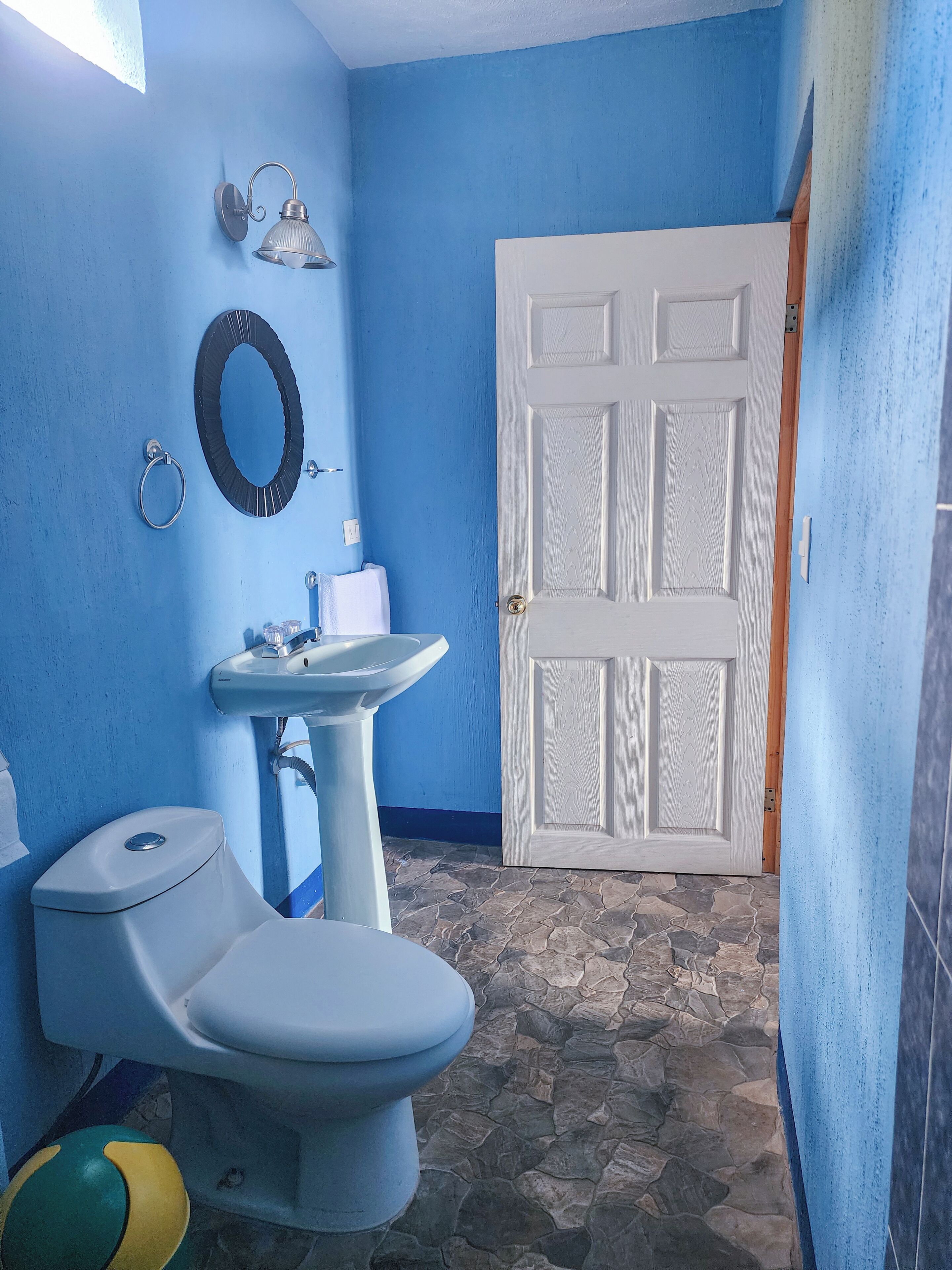 A bathroom with a toilet, sink, and a door.