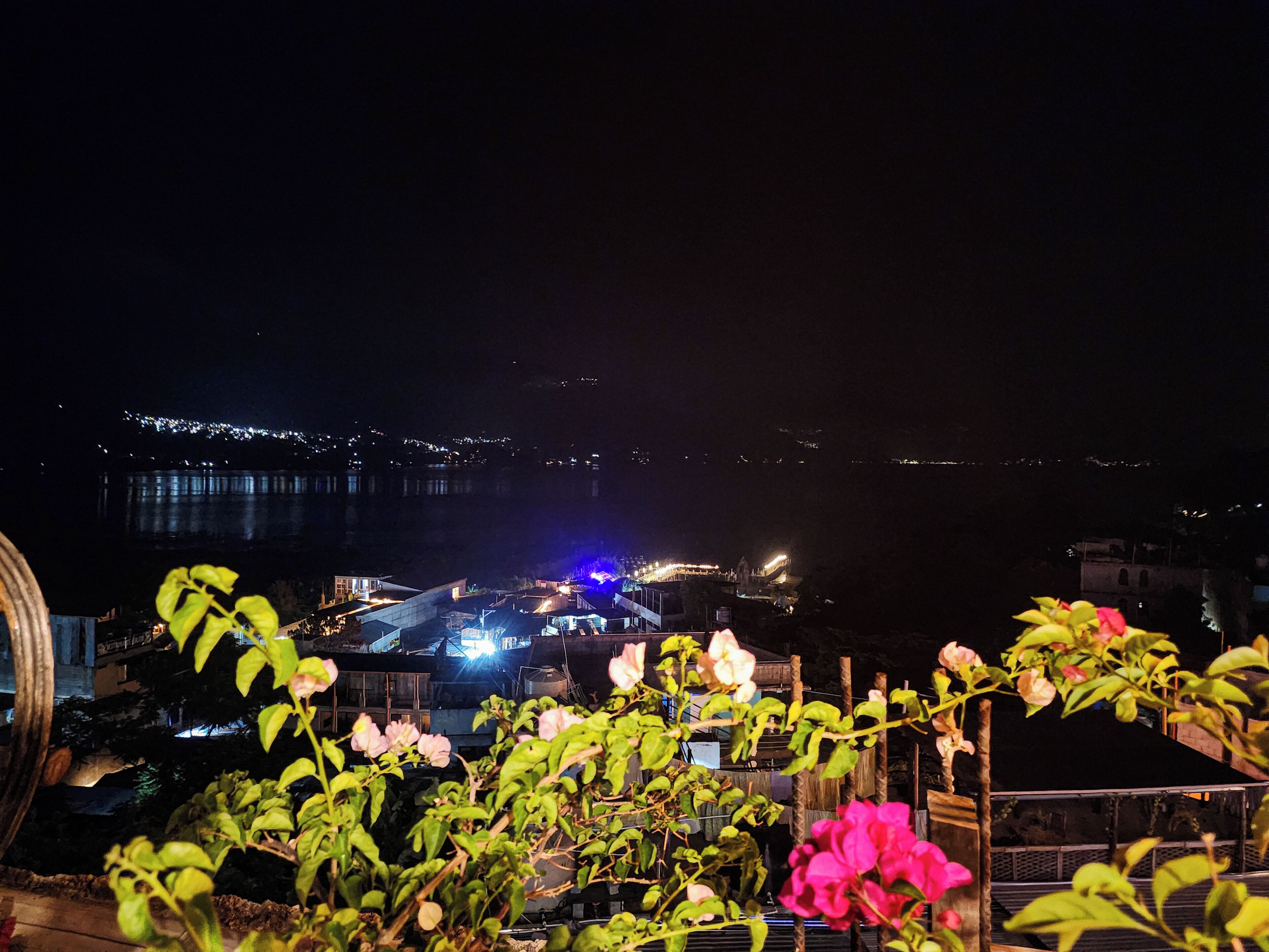 Vista nocturna de un paisaje urbano con edificios y un puente distante.
