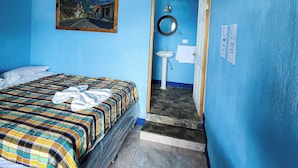 Une pièce comprenant un lit, un lavabo, un miroir et un tableau encadré accroché au mur.