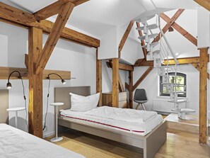A bedroom with a bed, a desk, a chair, and a window.