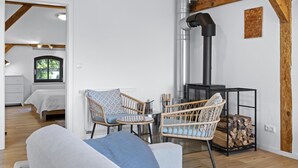 A modern interior with a fireplace, wicker furniture, and a view to a bedroom.