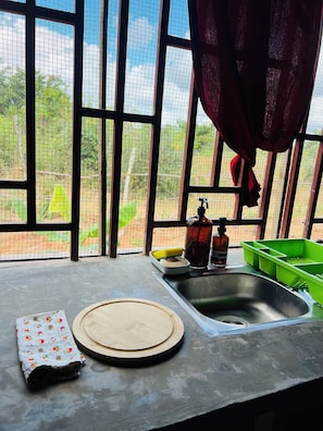 A kitchen with a sink, a cutting board, a cloth, and a bottle of soap.