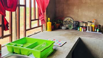 Una cocina con un lavabo, un escurreplatos verde y varios utensilios de cocina sobre la encimera.