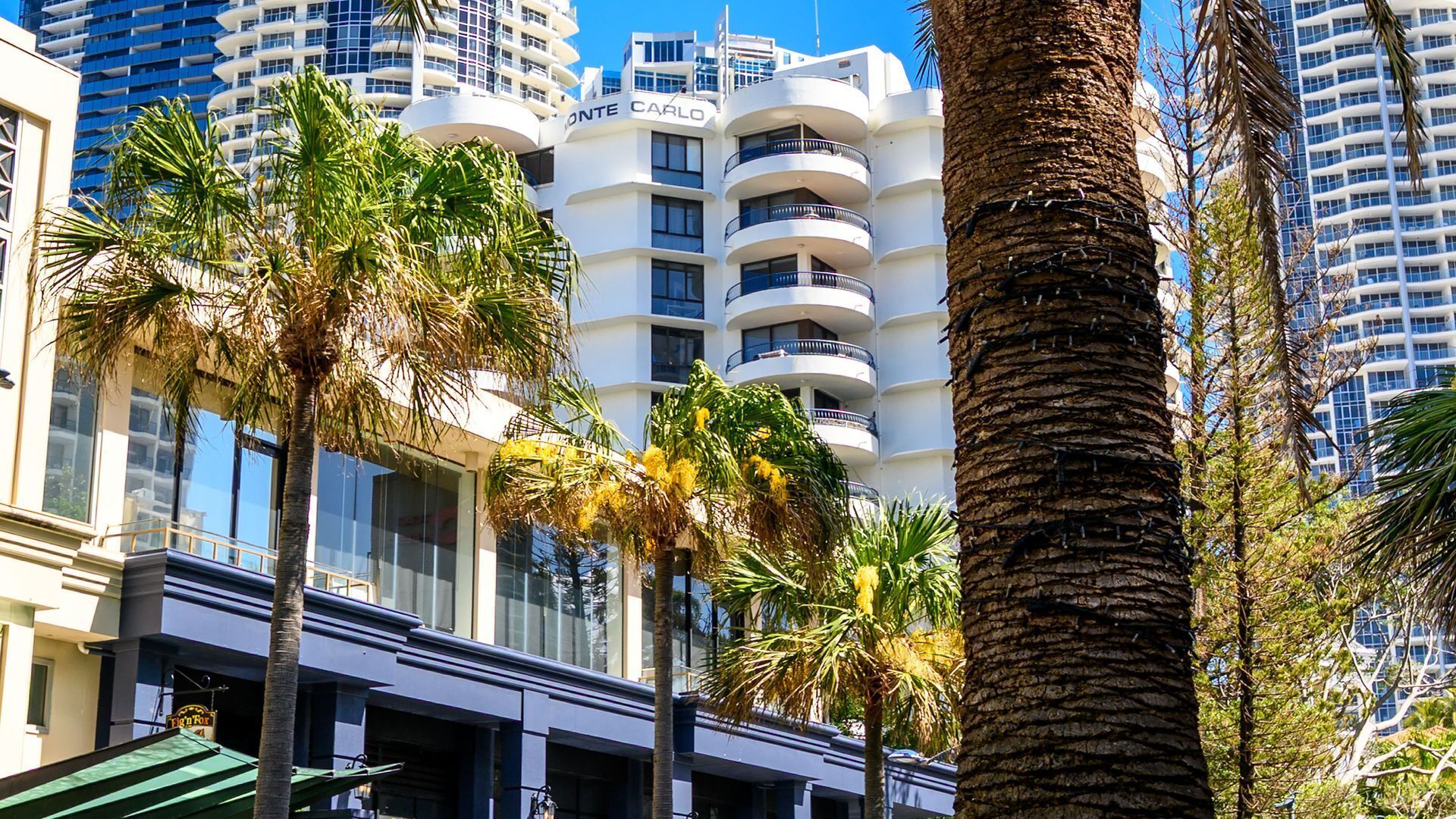 Un hôtel à plusieurs étages doté de balcons, de palmiers et d’une architecture moderne.