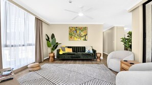 Ein modernes Wohnzimmer mit einem dunkelgrünen Sofa, einem weißen Sessel und einem Teppich mit geometrischem Muster.
