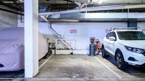 Eine Tiefgarage mit einem weißen SUV, einem Fahrrad und einem abgedeckten Gegenstand.